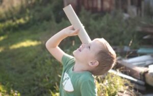 photo of young boy looking through a paper tube